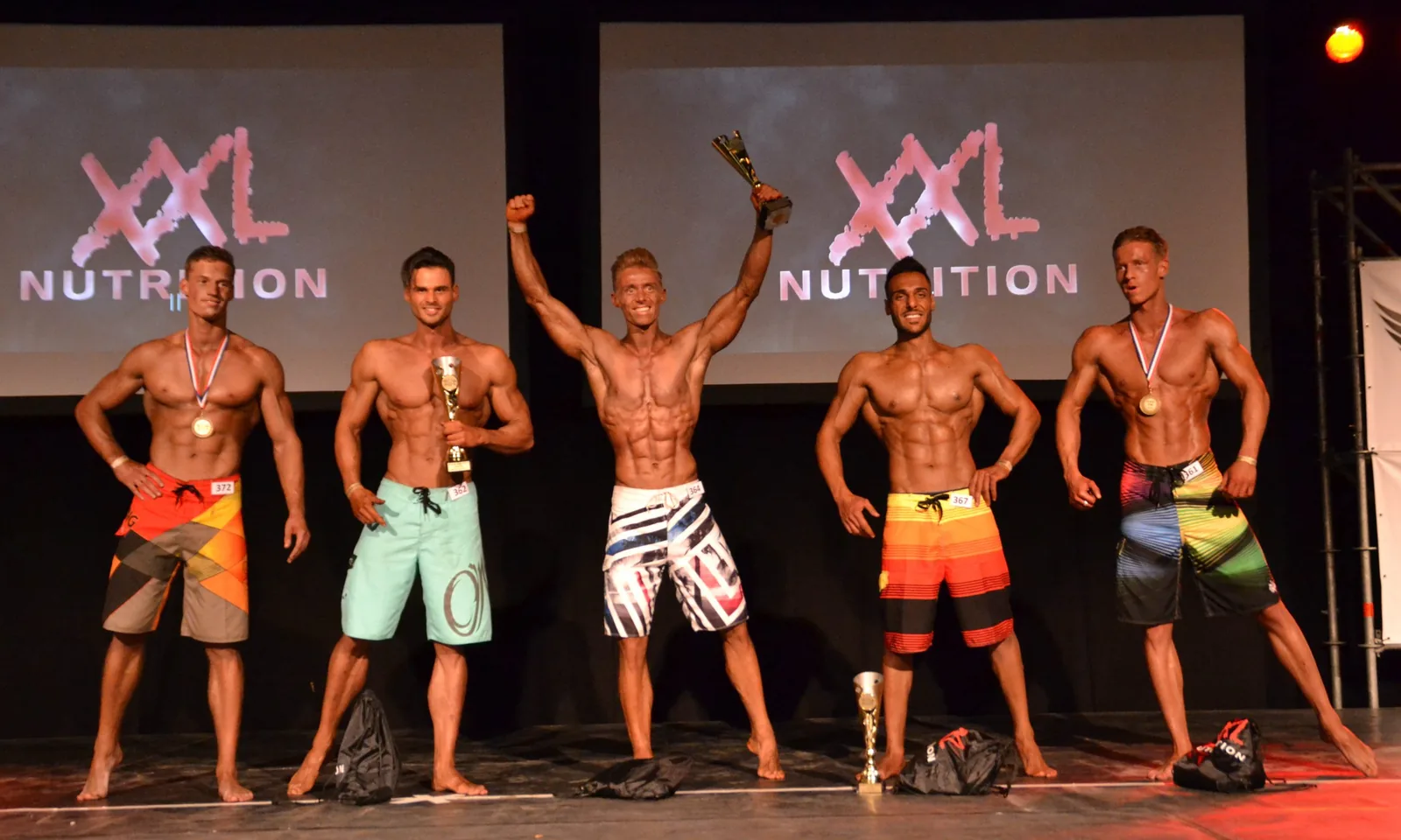 Jeroen Schilder in het midden van het podium met de beker omhoog, als winnaar Men&rsquo;s Physique op de SAP Cup